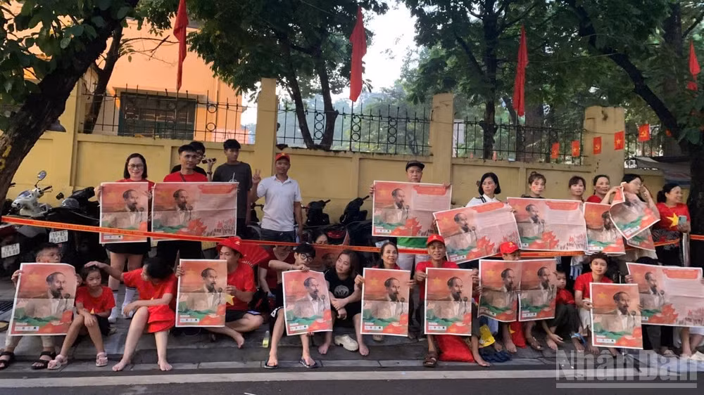 Người dân giơ cao tờ phụ san Báo Nhân Dân in ảnh Bác Hồ chào đón đoàn xe diễu binh trên đường Cửa Bắc.
