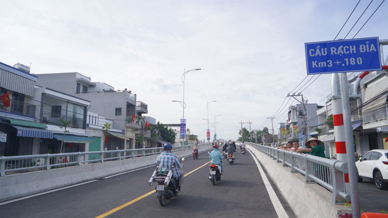 Đông đảo người dân phấn khởi đứng hai bên đường nhìn xe lưu thông qua lại.