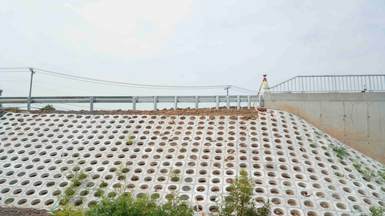 Mái taluy trên đường dẫn vào cầu đang được ốp gạch bê tông. Mái taluy trên đường dẫn vào cầu đang được ốp gạch bê tông.