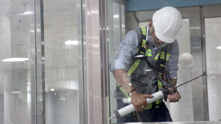 Công nhân thi công lắp cửa kính bên trong nhà ga Metro Bến Thành-Suối Tiên.