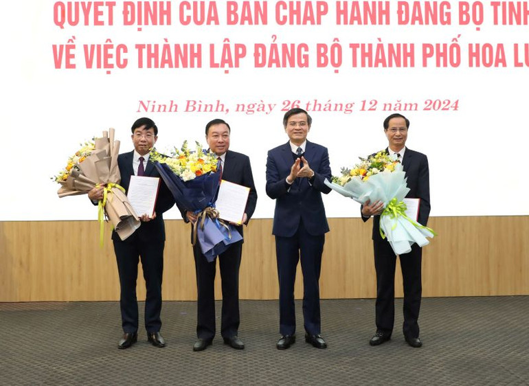 Đồng chí Đoàn Minh Huấn, Ủy viên Trung ương Đảng, Bí thư Tỉnh ủy Ninh Bình trao quyết định và tặng hoa chúc mừng các đồng chí Thường trực thành ủy Hoa Lư.