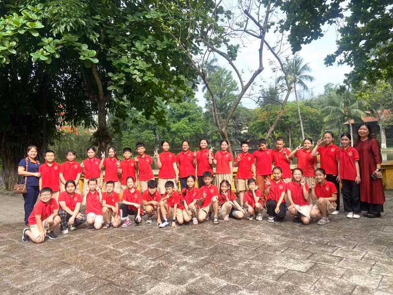 Đoàn học sinh chụp ảnh lưu niệm trước ao cá Bác Hồ.