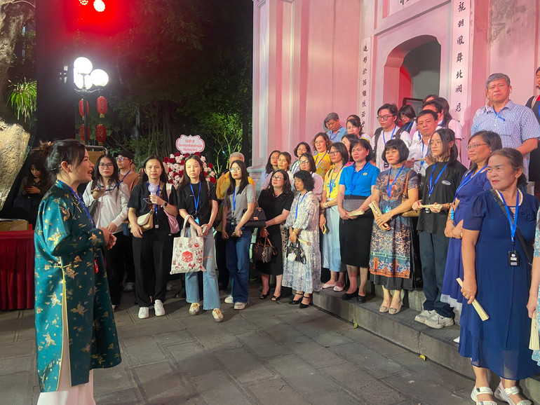 Du khách nghe thuyết minh trong tour đêm “Tiếng chuông Trấn Vũ”.