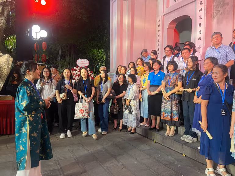 Du khách nghe thuyết minh trong tour đêm “Tiếng chuông Trấn Vũ”.