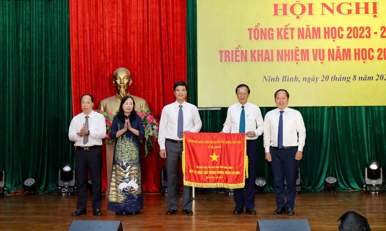 Thừa ủy quyền của Thủ tướng Chính phủ, Thứ trưởng Giáo dục và Đào tạo Phạm Ngọc Thưởng trao tặng Cờ thi đua của Chính phủ. (Ảnh: Minh Quang)