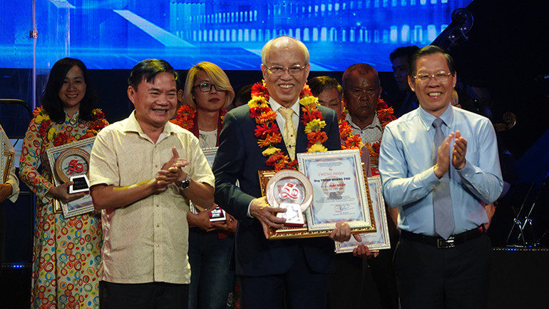 Chủ tịch Ủy ban nhân dân Thành phố Hồ Chí Minh Phan Văn Mãi (phải) và nhà văn Bùi Anh Tấn, Phó Chủ tịch Liên hiệp các Hội Văn học Nghệ thuật thành phố, Phó Chủ tịch Hội Nhà văn thành phố trao giải Nhất lĩnh vực văn học cho nhà văn Trình Quang Phú với tác phẩm "Theo dấu chân Người".