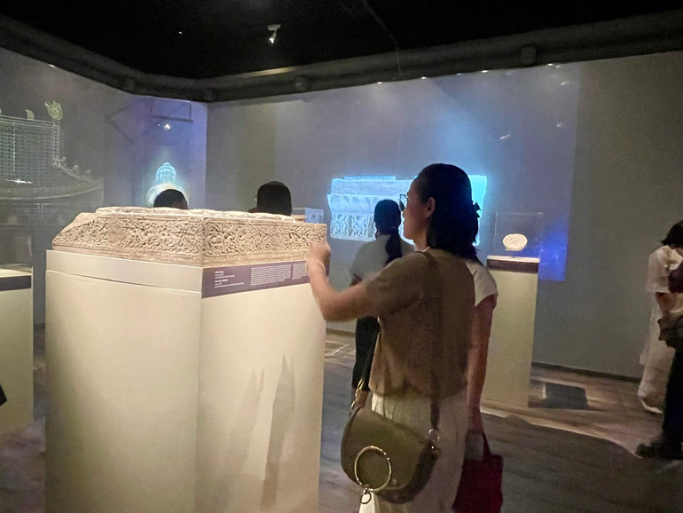 Khách tham quan tìm hiểu về bệ kê chân cột bằng đá tìm thấy tại chùa Phật Tích, huyện Tiên Du, tỉnh Bắc Ninh.