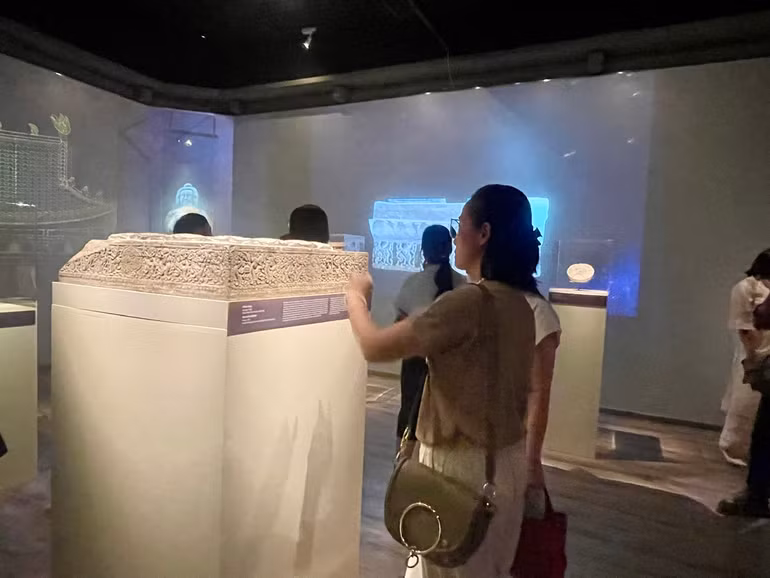 Khách tham quan tìm hiểu về bệ kê chân cột bằng đá tìm thấy tại chùa Phật Tích, huyện Tiên Du, tỉnh Bắc Ninh.