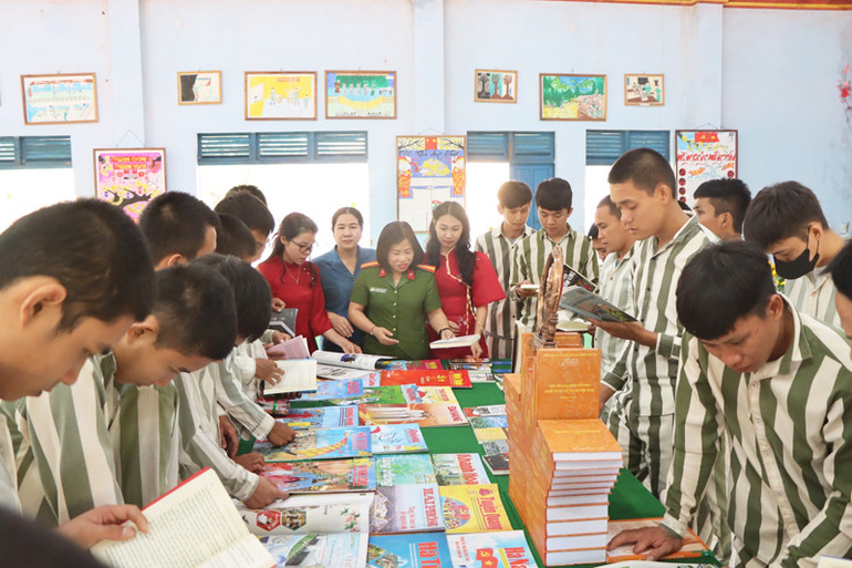 Cán bộ Trại giam Sông Cái và phạm nhân đọc báo Xuân Ất Tỵ 2025 tại nơi trưng bày. (Ảnh: NGUYỄN TRUNG)