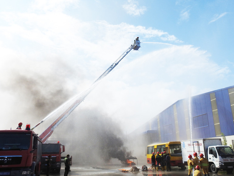 Các lực lượng được huy động tham gia chữa cháy tại buổi diễn tập dùng phương tiện chuyên dùng hiện đại cùng phối hợp phun nước để dập tắt đám cháy. (Ảnh: NGUYỄN TRUNG)