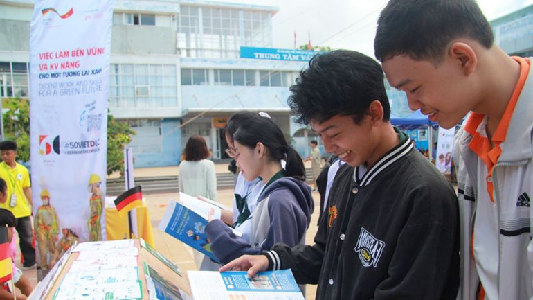 Học sinh, sinh viên ở Ninh Thuận xem tài liệu hướng dẫn về học tập, tìm việc làm bền vững và kỹ năng cho một tương lai xanh do Chương trình "Chuyến xe hướng nghiệp Đức" trưng bày.