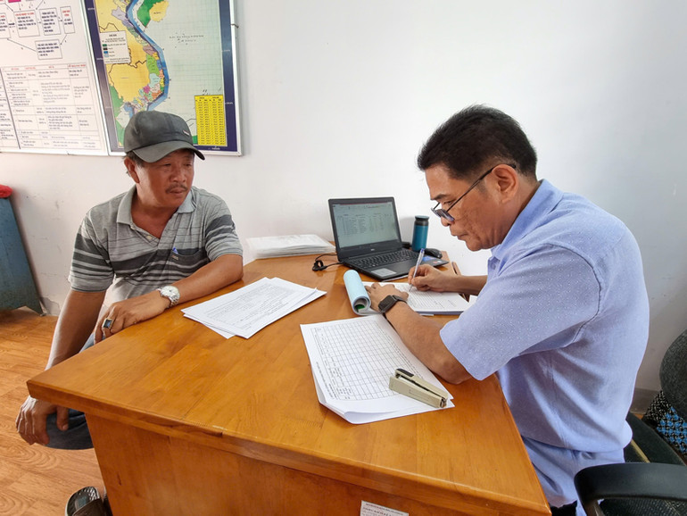 Cán bộ Ban Quản lý cảng Ninh Chử, xã Tri Hải, huyện Ninh Hải (Ninh Thuận), kiểm tra hồ sơ, nhật ký hoạt động khai thác thủy sản của ngư dân tại địa phương đã hết hạn để cấp lại giấy phép hoạt động, bảo đảm các thủ tục pháp lý cho ngư dân vươn khơi (Ảnh: NGUYỄN TRUNG)