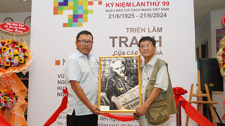 Nhà báo Huỳnh Dũng Nhân tặng Báo Nhân Dân bức tranh Bác Hồ đọc Báo Nhân Dân. (Ảnh: Thế Anh)