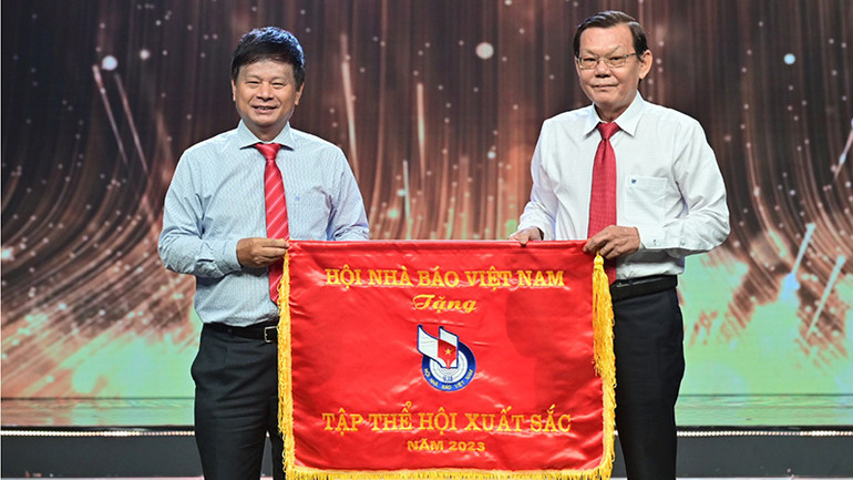 Ông Trần Trọng Dũng (bìa trái), Phó Chủ tịch Hội Nhà báo Việt Nam, phụ trách phía nam trao Cờ thi đua tập thể xuất sắc năm 2023 cho Hội Nhà báo Thành phố Hồ Chí Minh. (Ảnh: Quốc Thanh)