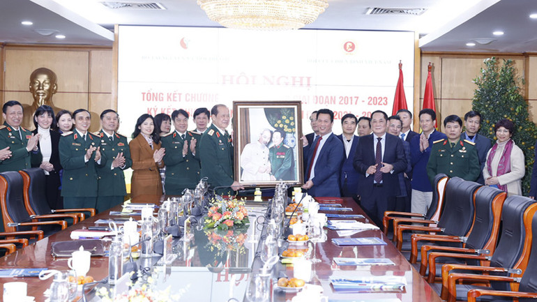 Các đại biểu chụp ảnh lưu niệm bên bức tranh Chủ tịch Hồ Chí Minh và Đại tướng Võ Nguyên Giáp.