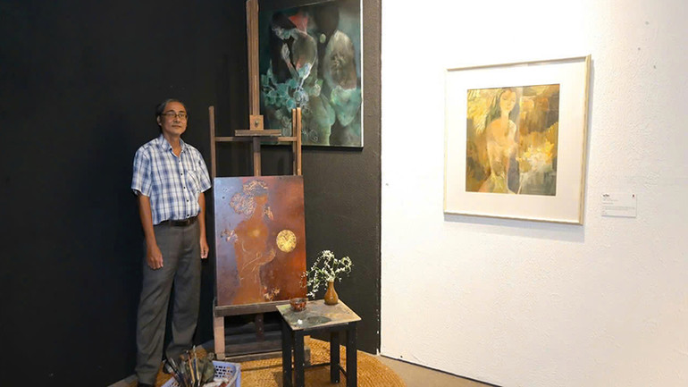 Họa sĩ Hồ Hồng Lĩnh, con trai họa sĩ Hồ Hữu Thủ, bên hai bức tranh dang dở của cha mình được bố trí trong không gian trưng bày . (Ảnh: BTC).