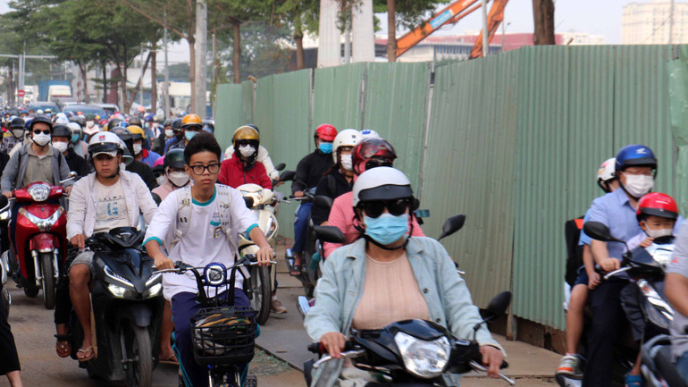 Người dân di chuyển chậm chạp qua đường Nguyễn Văn Linh khu vực công trình dự án hầm chui Nguyễn Văn Linh-Nguyễn Hữu Thọ, quận 7. Phía cần cẩu là hầm chui đang được xây dựng, công trình đang làm rào chắn chiếm nửa đường khiến việc lưu thông qua lại của người dân gặp khó khăn.