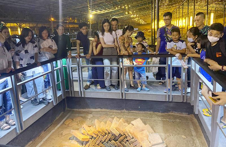 Khách du lịch tham quan giếng cổ trong Hoàng thành Thăng Long (Hà Nội). (Ảnh CHÍ DŨNG)