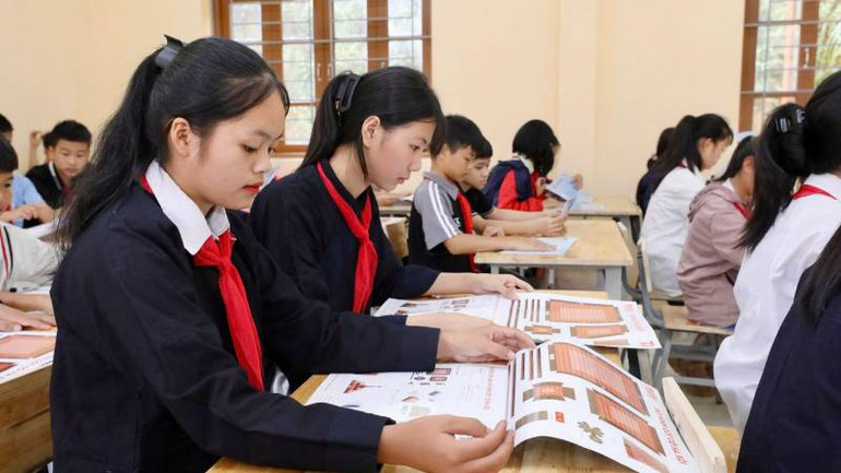 Các em học sinh trường Trung học cơ sở Tân Văn, huyện Bình Gia (Lạng Sơn), tiếp nhận ấn phẩm đặc biệt " Cột cờ Hà Nội".