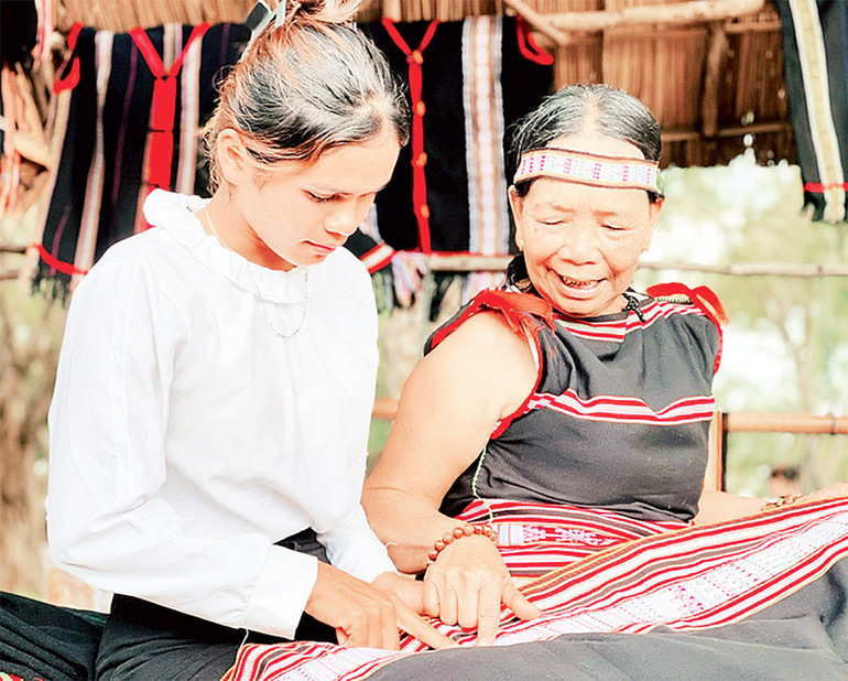 Nghệ nhân truyền dạy cách dệt hoa văn trên thổ cẩm truyền thống cho thế hệ trẻ.