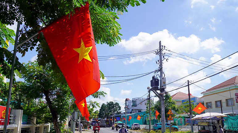 Đường Lê Văn Lương, huyện Nhà Bè thêm sinh động khi được treo cờ đỏ sao vàng dọc hai bên đường để chào đón Tết Độc lập.