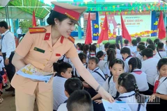 Cán bộ Cảnh sát giao thông phát tờ rơi tuyên truyền tại Trường tiểu học Tân Hưng Tây A, xã Nguyễn Việt Khái, tỉnh Cà Mau.
