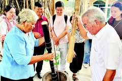 Vợ chồng ông Thạch Sang giã cốm dẹp cho khách du lịch xem.