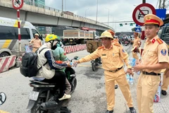 Cảnh sát giao thông Công an tỉnh Đồng Nai phát nước suối cho người dân trên Quốc lộ 1A.