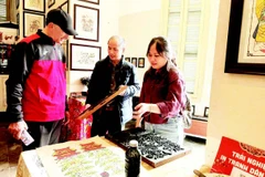 Võ Ca Dao hướng dẫn cho du khách nước ngoài trải nghiệm in tranh mộc bản.