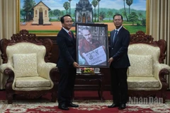 Phó Bí thư Thường trực Thành ủy Đà Nẵng Nguyễn Đình Vĩnh trao tặng bức ảnh Bác Hồ đọc Báo Nhân Dân cho lãnh đạo tỉnh Savannakhet. (Ảnh: ANH ĐÀO)