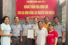 Đồng chí Vũ Văn Tài, Bí thư Đảng ủy Chi đội Kiểm ngư số 3 (thứ hai từ trái sang) trao kinh phí hỗ trợ nhà đồng đội cho gia đình đồng chí Nguyễn Văn Hoàng. (Ảnh: TIẾN DŨNG)