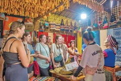 Du khách nước ngoài thích thú với những sản phẩm vải lanh của Lùng Tám. 