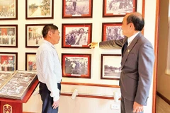 Ông Phùng Văn Tiệp (bên phải), Trưởng phòng Văn hóa-Xã hội xã Dân Hòa giới thiệu cho khách tham quan các hình ảnh về Chủ tịch Hồ Chí Minh tại Nhà lưu niệm Chủ tịch Hồ Chí Minh tại xã Dân Hòa.