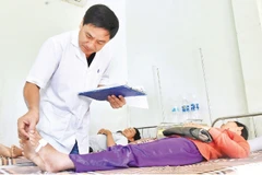 Thượng tá, bác sĩ chuyên khoa I Nguyễn Văn Tuấn, Trưởng Khoa điều trị rắn cắn khám bệnh cho bệnh nhân.