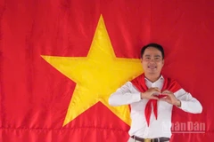 Tiến sĩ Võ Văn Sơn, giảng viên trẻ của Trường đại học Tiền Giang chụp ảnh cùng cờ Tổ quốc.
