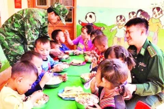 Thiếu tá Cầm Bá Thành (bên phải ảnh) cùng với đồng đội thực hiện “Bữa sáng cho em” tại điểm Trường mầm non Buốc Pát.