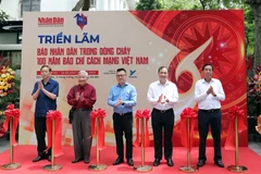 Đồng chí Lê Quốc Minh, Ủy viên Trung ương Đảng, Tổng Biên tập Báo Nhân Dân, Phó Trưởng ban Tuyên giáo và Dân vận Trung ương, Chủ tịch Hội Nhà báo Việt Nam (đứng chính giữa), đồng chí Hoàng Trung Dũng, Ủy viên Ban Chấp hành Trung ương Đảng, Tổng Biên tập Tạp chí Cộng sản (thứ hai, từ phải sang) cùng các đồng chí nguyên Tổng Biên tập Báo Nhân Dân cắt băng khai mạc Triển lãm. (Ảnh KHIẾU MINH)