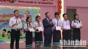 Đại sứ Việt Nam tại Lào Nguyễn Minh Tâm trao tặng phần thưởng cho các em học sinh có thành tích tốt trong năm học 2024-2025. (Ảnh: HẢI TIẾN)