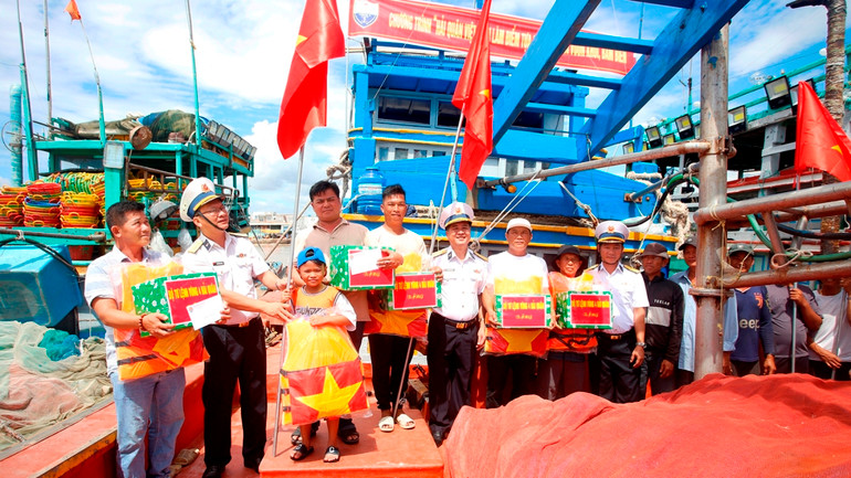 Tặng áo phao và cờ Tổ quốc cho các ngư dân tại cảng cá Phan Rí Cửa.