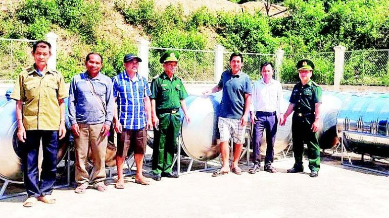 Đại diện Đồn Biên phòng Na Loi phối hợp với chính quyền địa phương trao tặng bồn chứa nước sạch cho người dân. (Ảnh HẢI THƯỢNG)