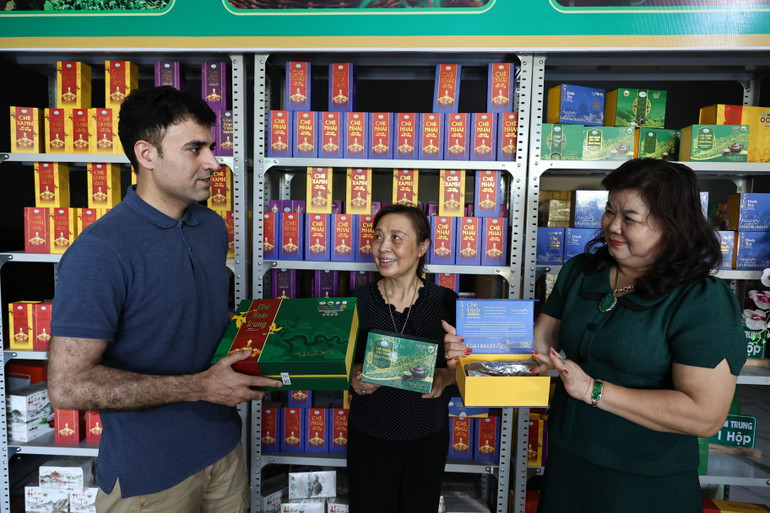 Chị Bùi Thị Mão giới thiệu sản phẩm chè Đinh cao cấp với anh Assad người Afghanistan nhằm mở rộng thị trường tiêu thụ.