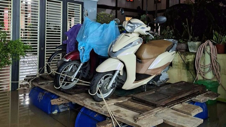 Người dân "sáng kiến" ra mô hình đưa xe máy lên trên phao nổi để tránh bị thiệt hại do nước lũ (Ảnh: CTV)