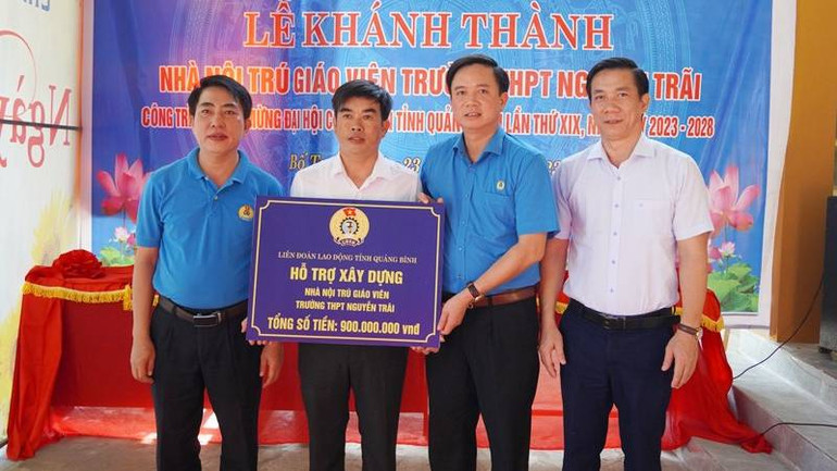 Chủ tịch Liên đoàn Lao động Quảng Bình Phạm Tiến Nam (áo xanh, giữa) trao kinh phí hỗ trợ xây nhà nội trú cho giáo viên ở huyện Bố Trạch.