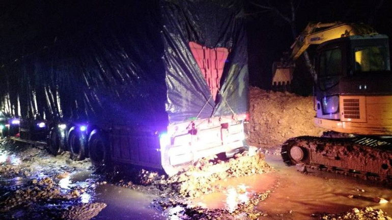 Xử lý đất đá trên mặt đường để cứu hộ xe tải chở hàng đang bị mắc kẹt trên quốc lộ 12A vào rạng sáng 26/9.