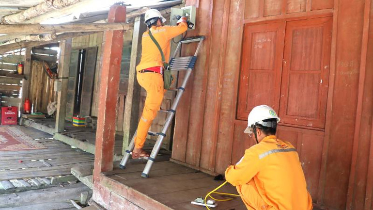 Công nhân điện lực hỗ trợ đấu nối sau công tơ để giúp đồng bào sử dụng điện an toàn.