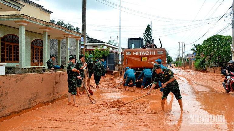 Cán bộ chiến sĩ Ban Chỉ huy Quân sự thành phố Phan Thiết hỗ trợ dân dọn dẹp bùn cát tràn vào nhà.