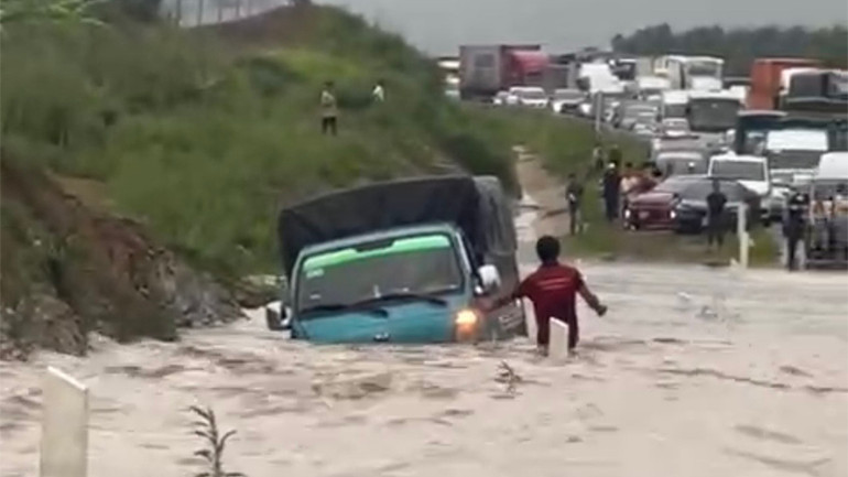 Một xe tải nhẹ cố vượt qua đoạn ngập nhưng bị nước dâng cao làm trôi dạt vào lề.