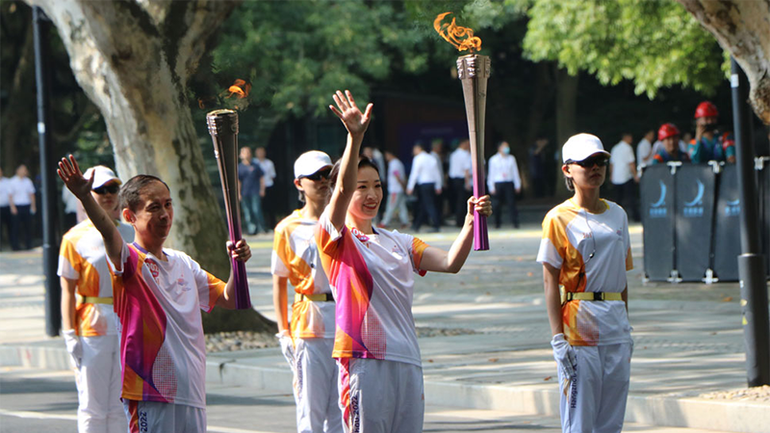 Thành viên rước đuốc ASIAD 19 vẫy tay chào khán giả. (Ảnh: people.com.cn)