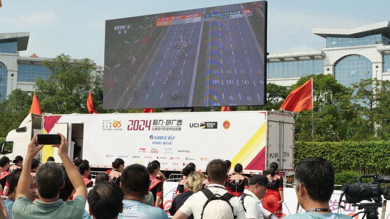 Nhiều người dân theo dõi cuộc đua qua màn hình tivi đặt ngoài trời được truyền hình trực tiếp.