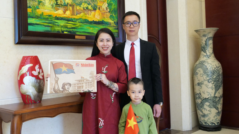 Gia đình anh chị Hoàng Hà-Nhật Linh chụp ảnh với ấn phẩm phụ san đặc biệt Kỷ niệm 50 năm Giải phóng miền nam, thống nhất đất nước của Báo Nhân Dân.